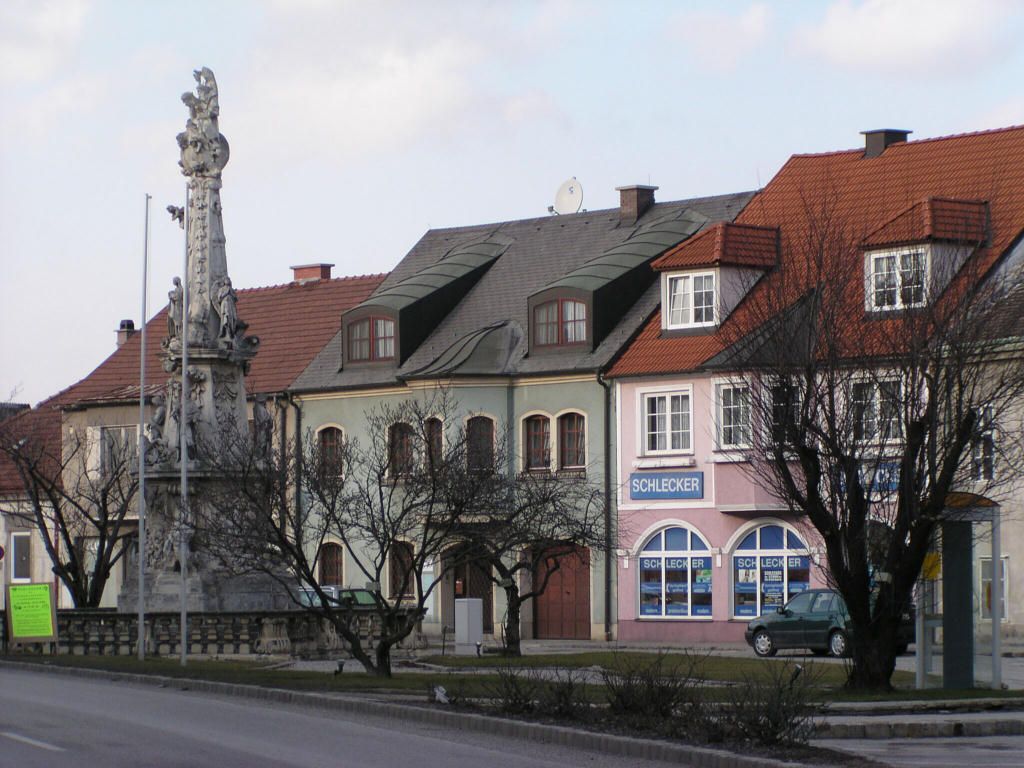 Straßenszene in Ebenfurth mit historischen Gebäuden und einer Statue.