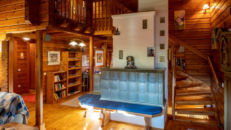 Gem&uuml;tliches Wohnzimmer mit Kachelofen, Holzw&auml;nden und Treppe.