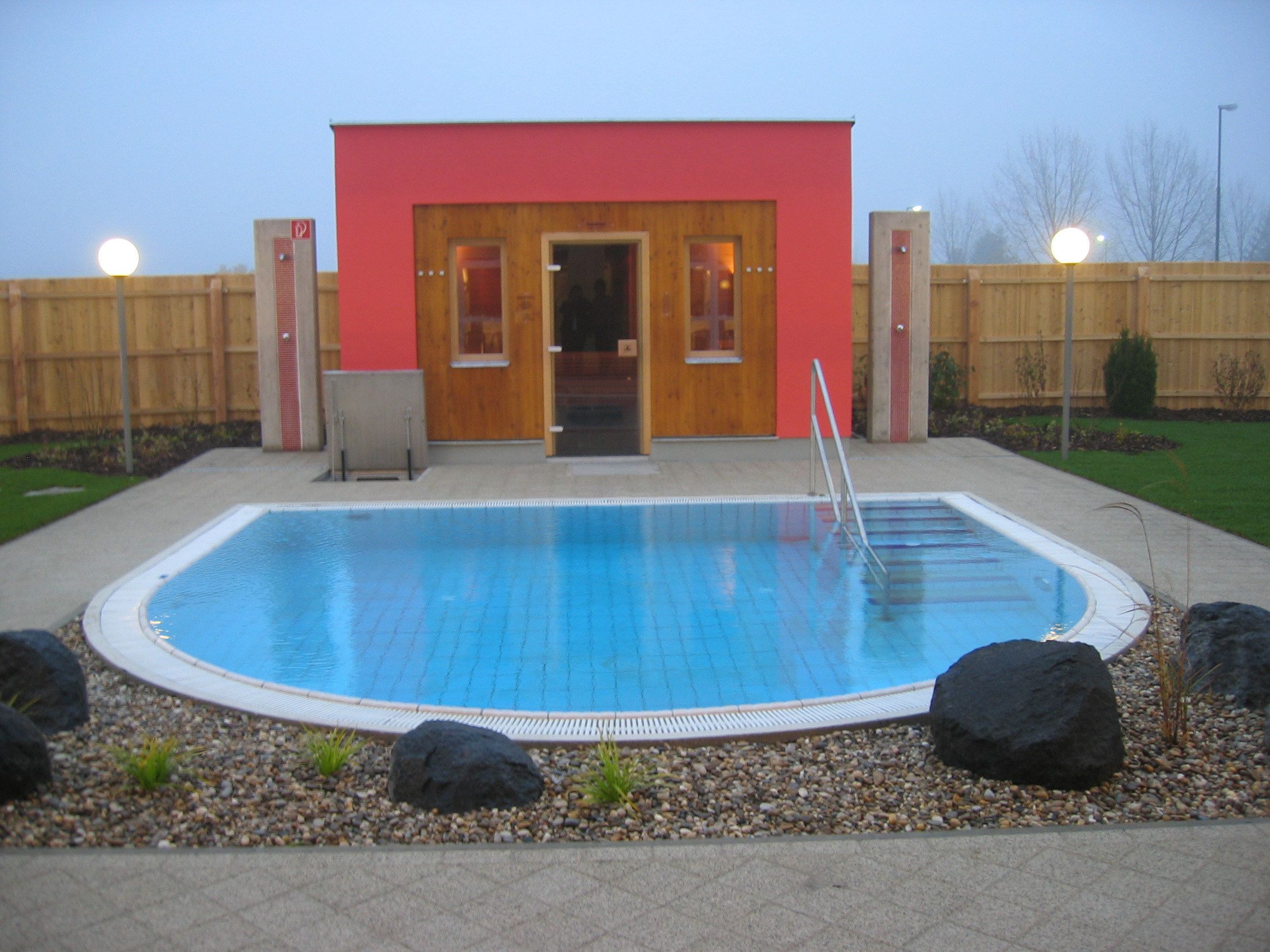 Außenansicht einer Sauna mit kleinem Pool und Garten.