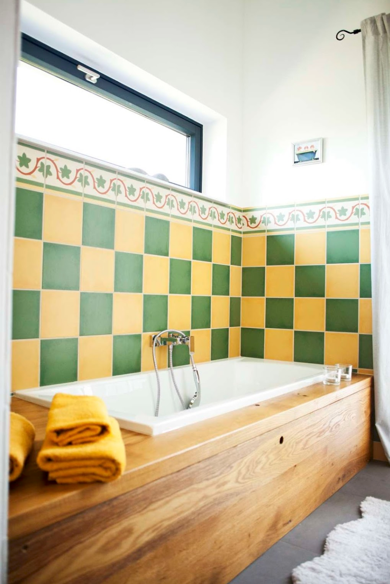 Badezimmer mit Badewanne, gelb-grünen Fliesen und Holzverkleidung.