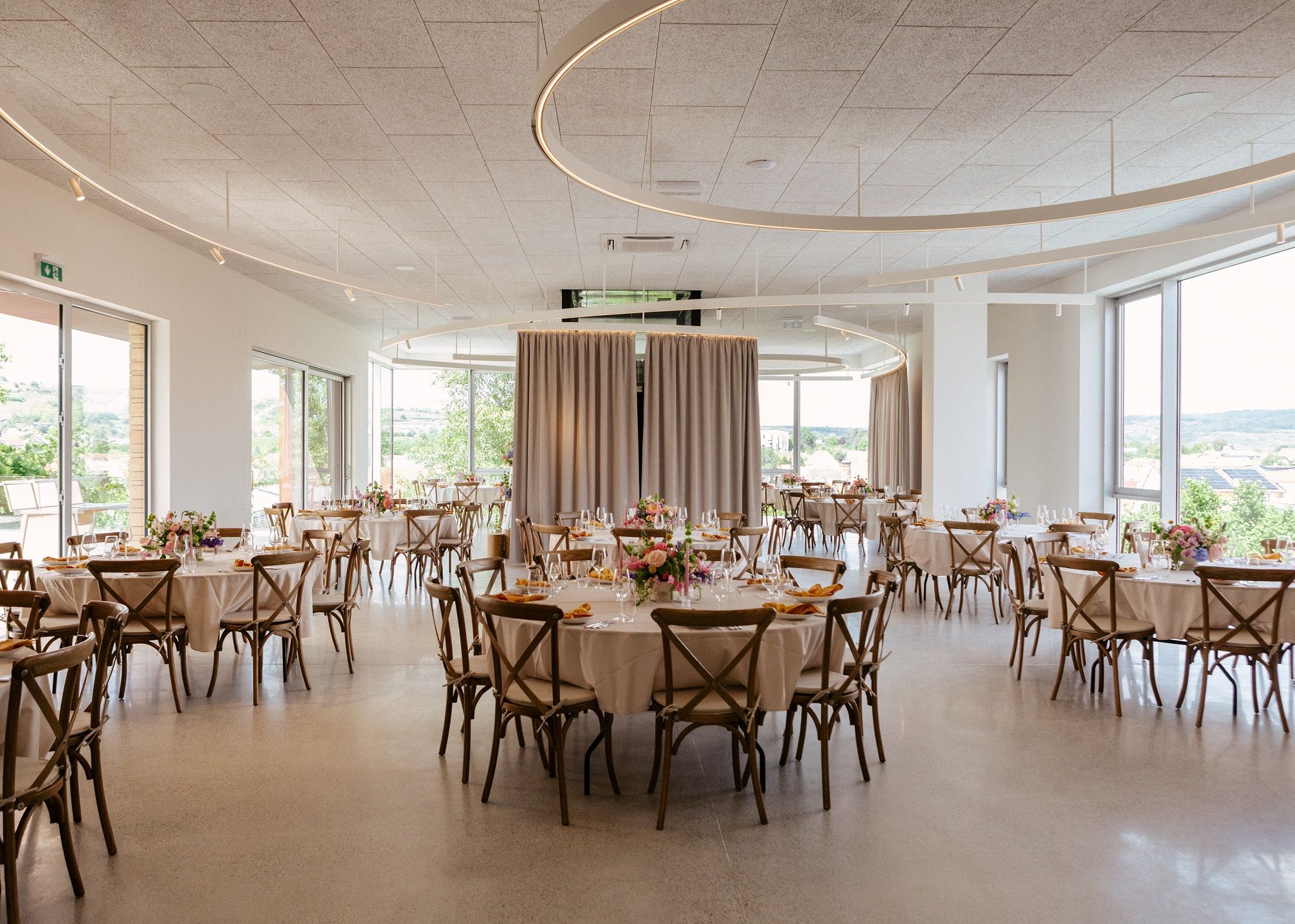 Eleganter Veranstaltungsraum mit runden Tischen, Stühlen und Blumendekoration.