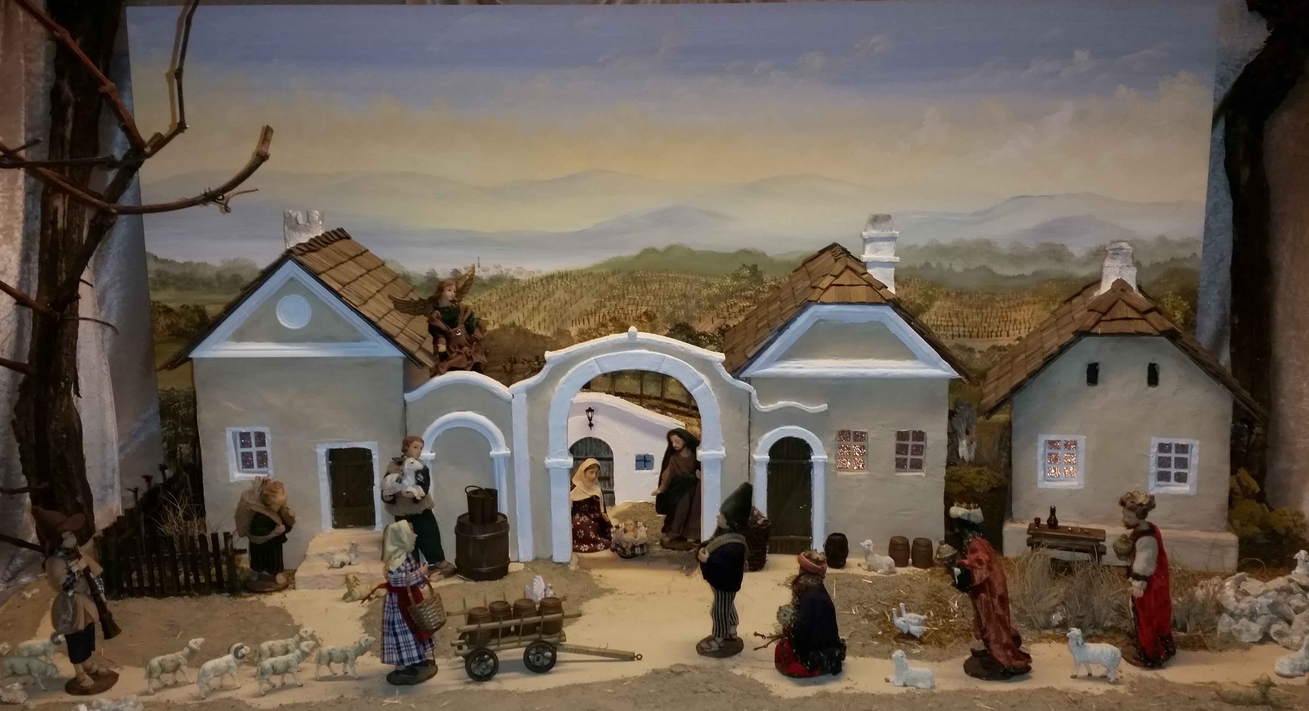 Weihnachtskrippe mit Figuren und Gebäuden in ländlicher Szenerie.