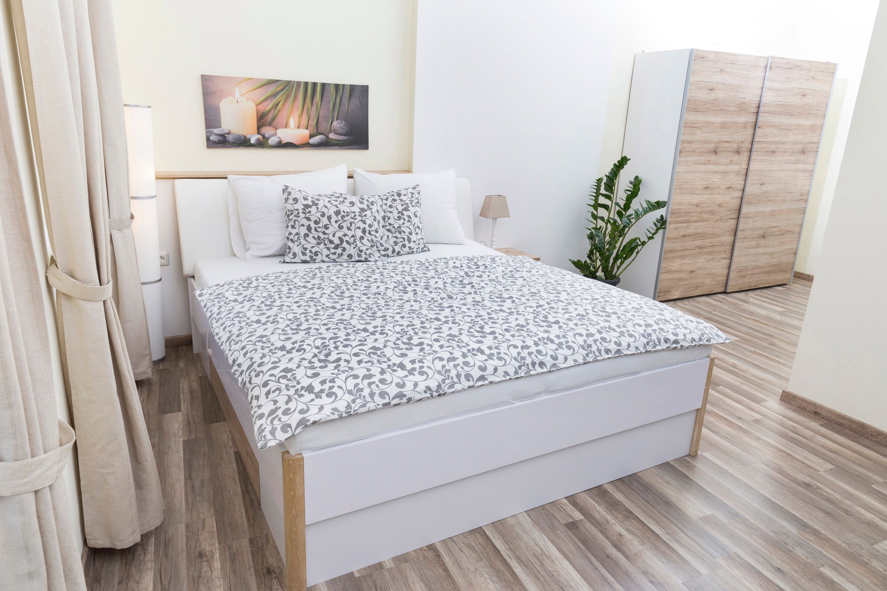 Modernes Schlafzimmer mit Doppelbett, Pflanzen und Schrank.