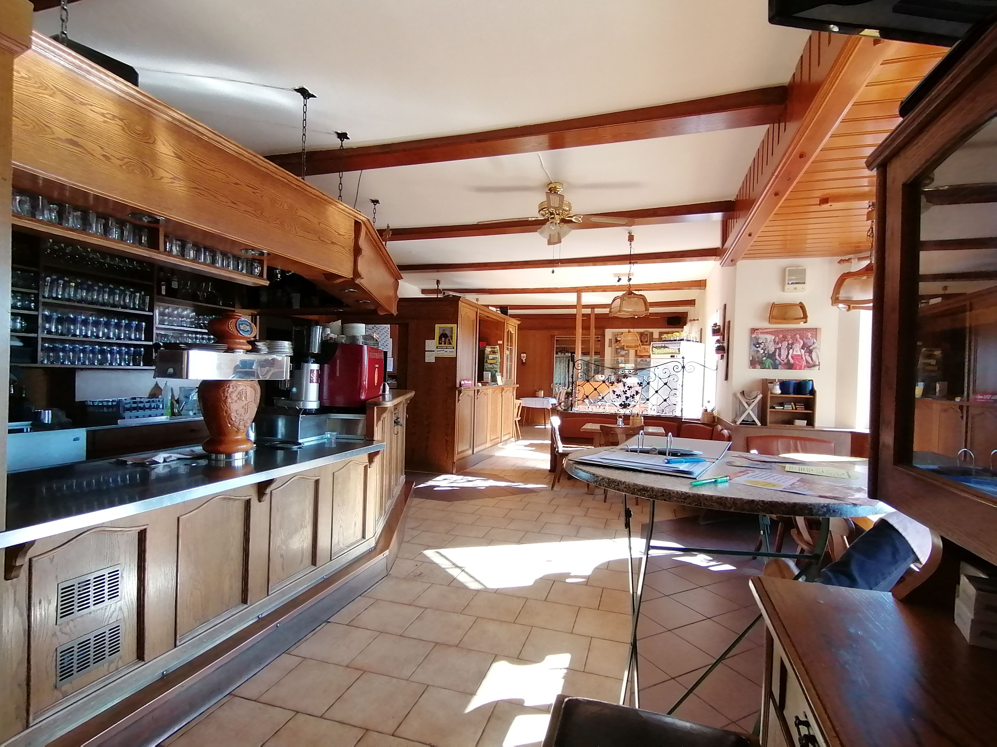 Innenansicht einer traditionellen Gaststube mit Holzmöbeln und Theke.