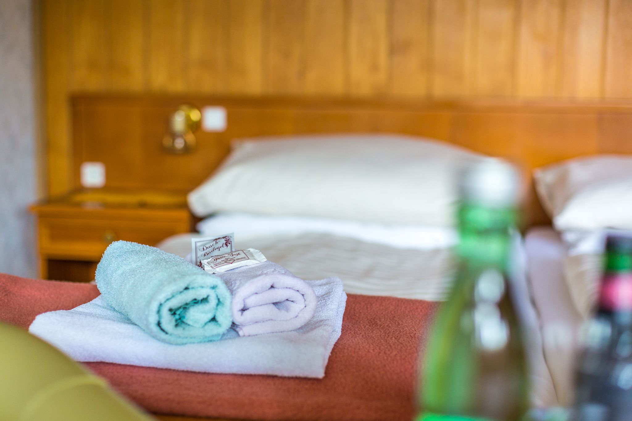 Hotelzimmer mit Bett, Handtüchern und Wasserflaschen.