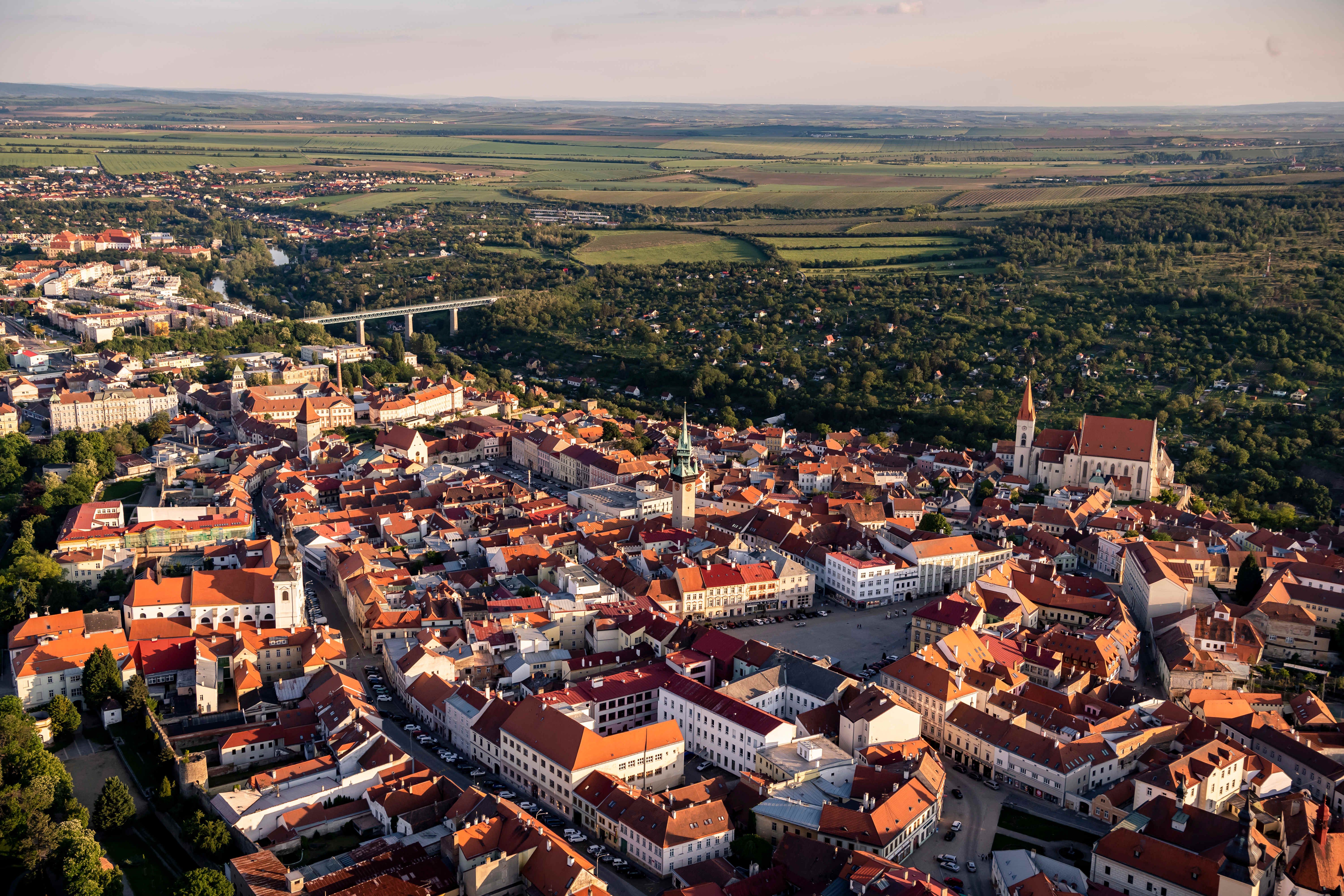Luftaufnahme der Stadt Znaim mit roten Dächern und umliegender Landschaft.