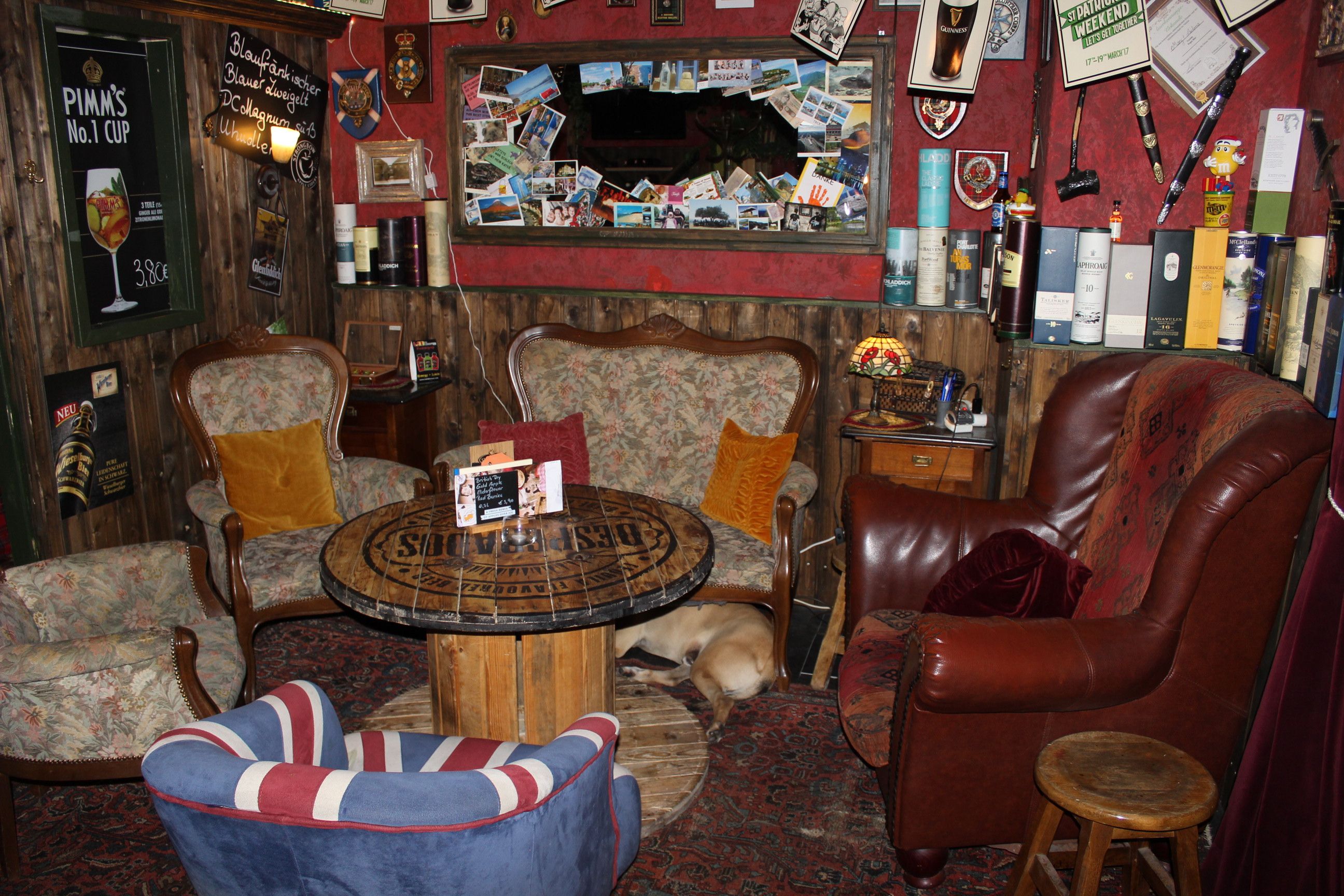 Gemütlicher Raum mit Sesseln, Tisch und Hund auf Teppich.