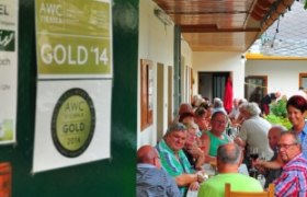 Menschen sitzen an einem langen Tisch in einem &uuml;berdachten Au&szlig;enbereich eines Restaurants.