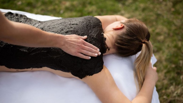 Person erh&auml;lt eine Moorpackung auf dem R&uuml;cken im Freien.