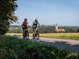 Radfahrer genießen die frische Luft und die malerische Landschaft entlang des Kamptal Radwegs. Umgeben von sanften Hügeln und üppigen Wiesen, strahlt die Umgebung eine einladende Ruhe aus, die zum Verweilen einlädt.