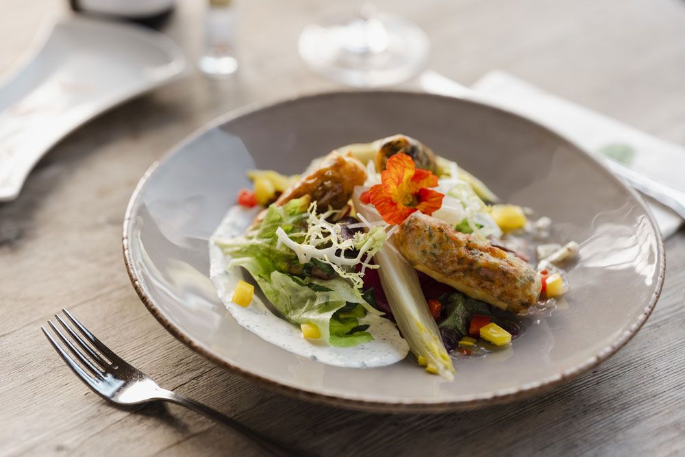 Ein Teller mit Frühlingsrollen, Salat und essbaren Blüten.