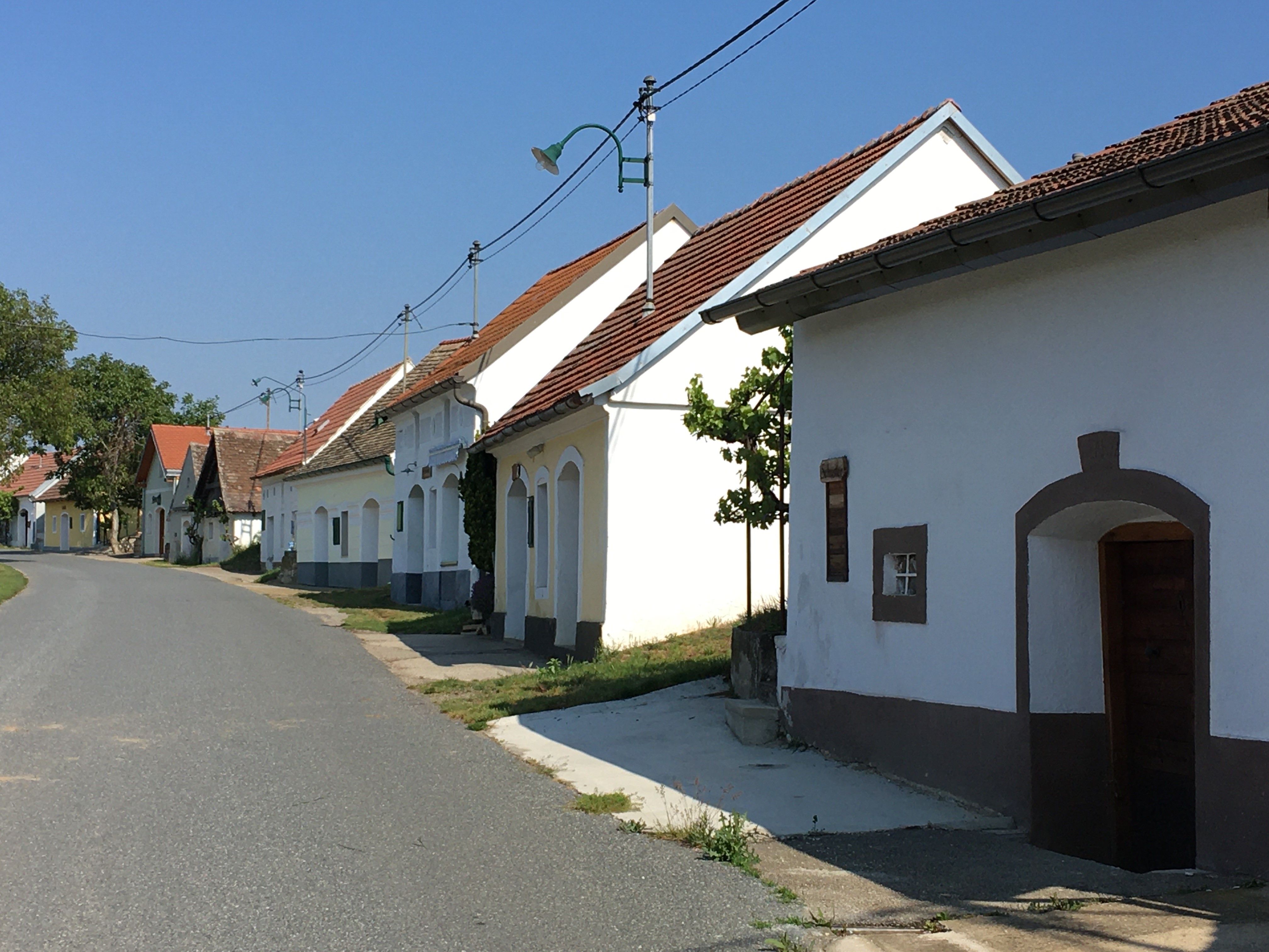 Eine ruhige Straße mit traditionellen, weiß getünchten Häusern und roten Dächern in einer ländlichen Umgebung.