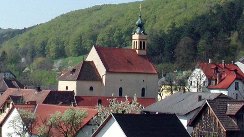 Wallfahrtskirche Maria Raisenmarkt in einer l&auml;ndlichen Umgebung mit H&uuml;geln im Hintergrund.