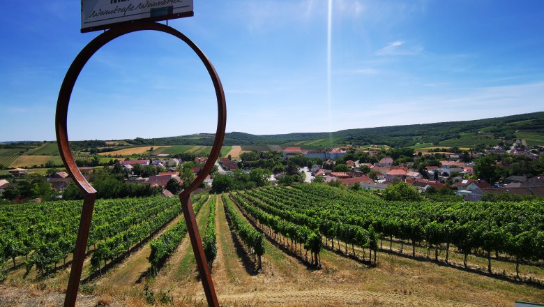 Blick auf Weinberge und Dorf durch ein gro&szlig;es Schl&uuml;sselloch-Symbol in Mailberg.