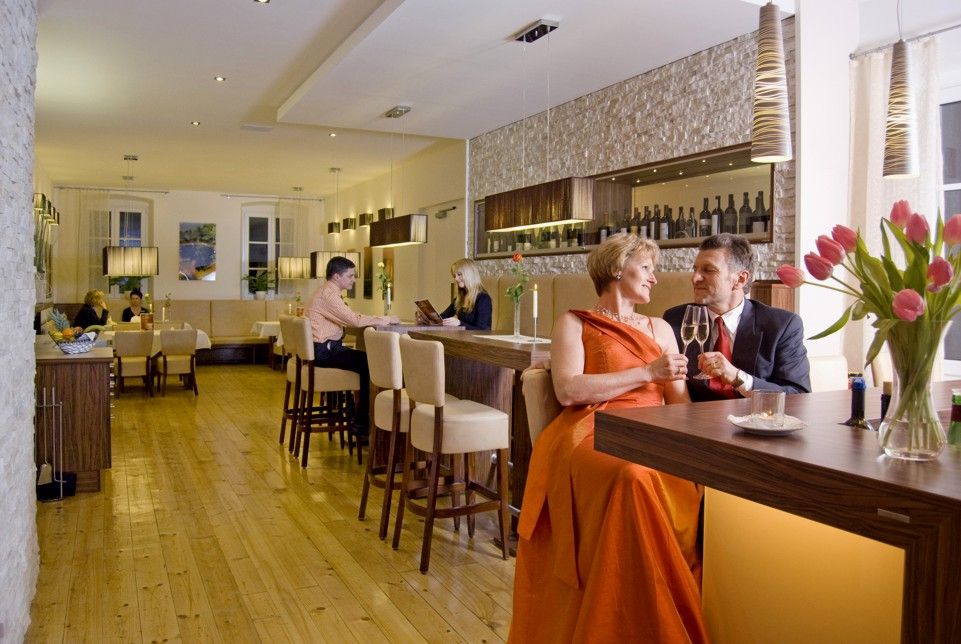 Ein elegantes Restaurant mit Paaren an Tischen und einer Bar.