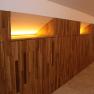 Holzverkleidete Wand mit indirekter Beleuchtung in einem Flur.