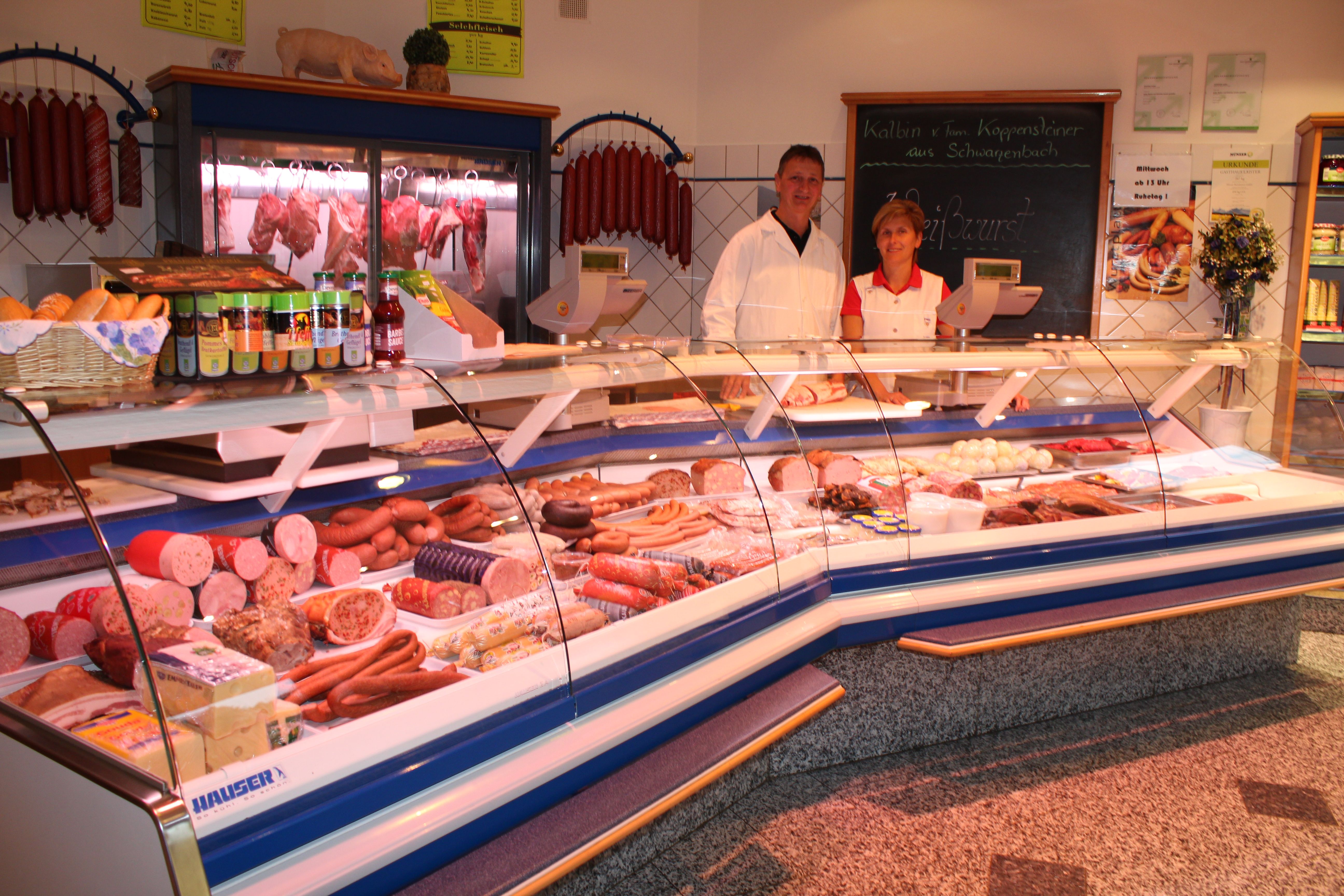 Zwei Personen hinter einer Fleischtheke in einer Metzgerei.