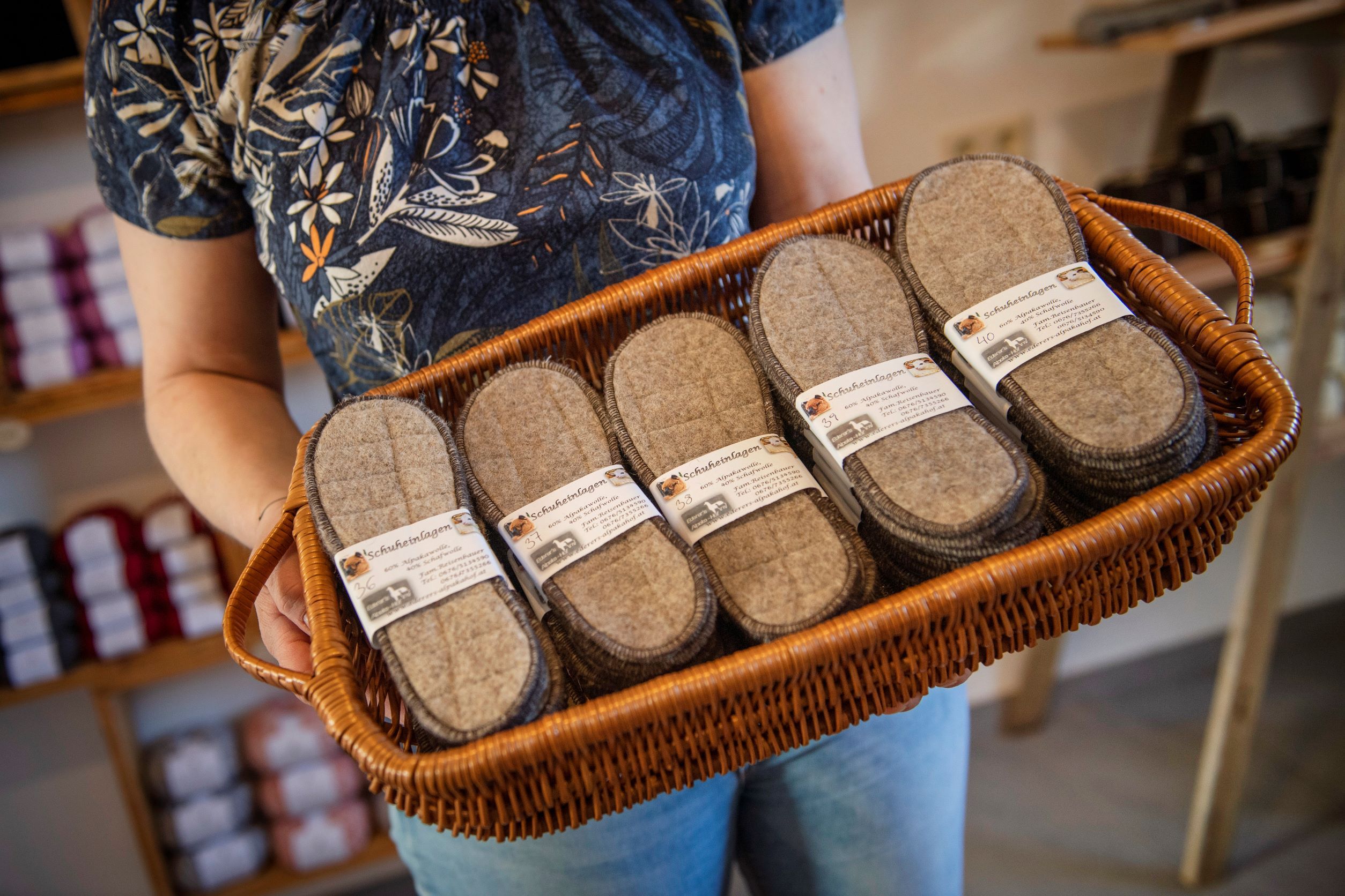 Person hält einen Korb mit Filzschuheinlagen in einem Hofladen.