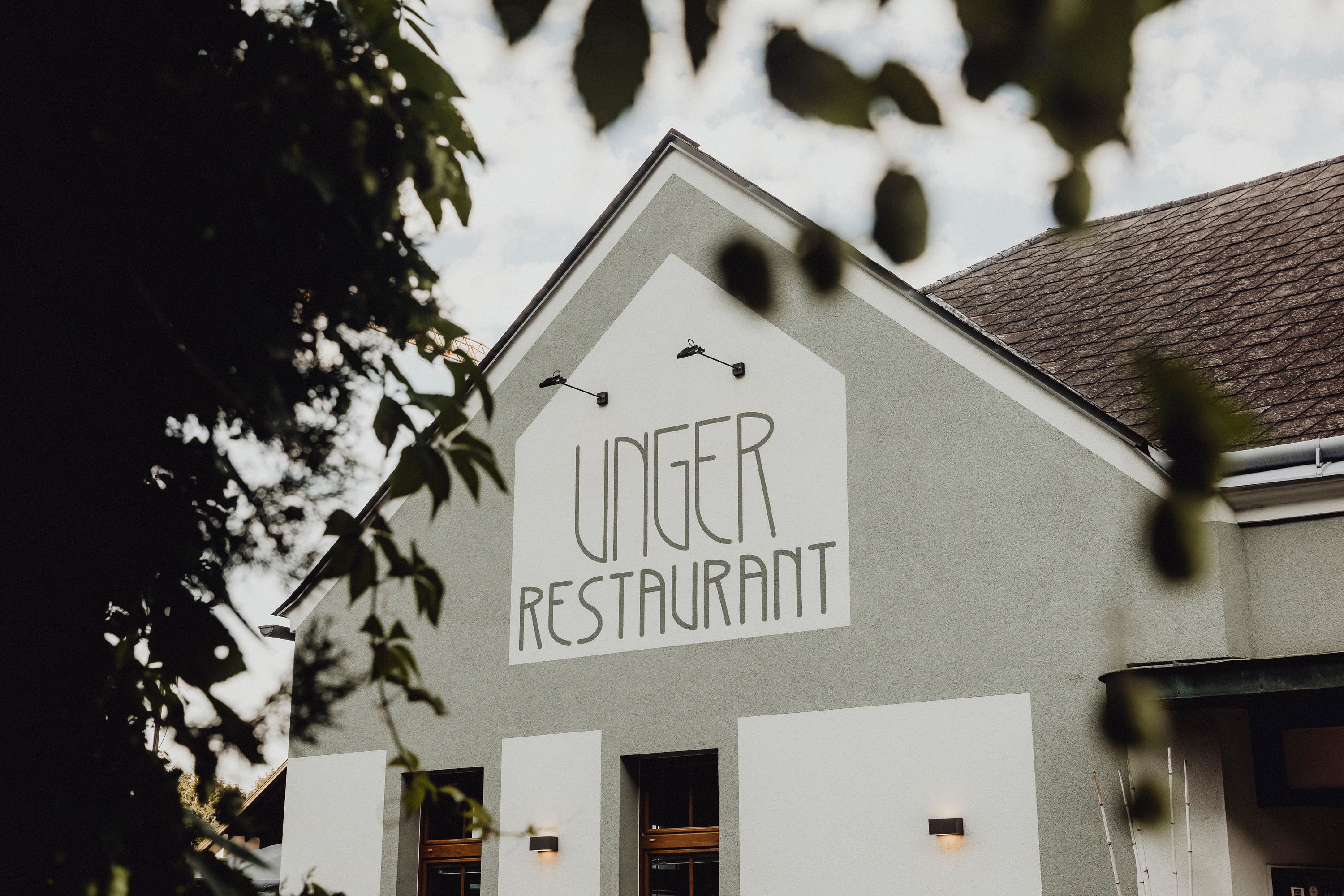 Außenansicht des Unger Restaurants mit grünem Gebäude und Schriftzug.