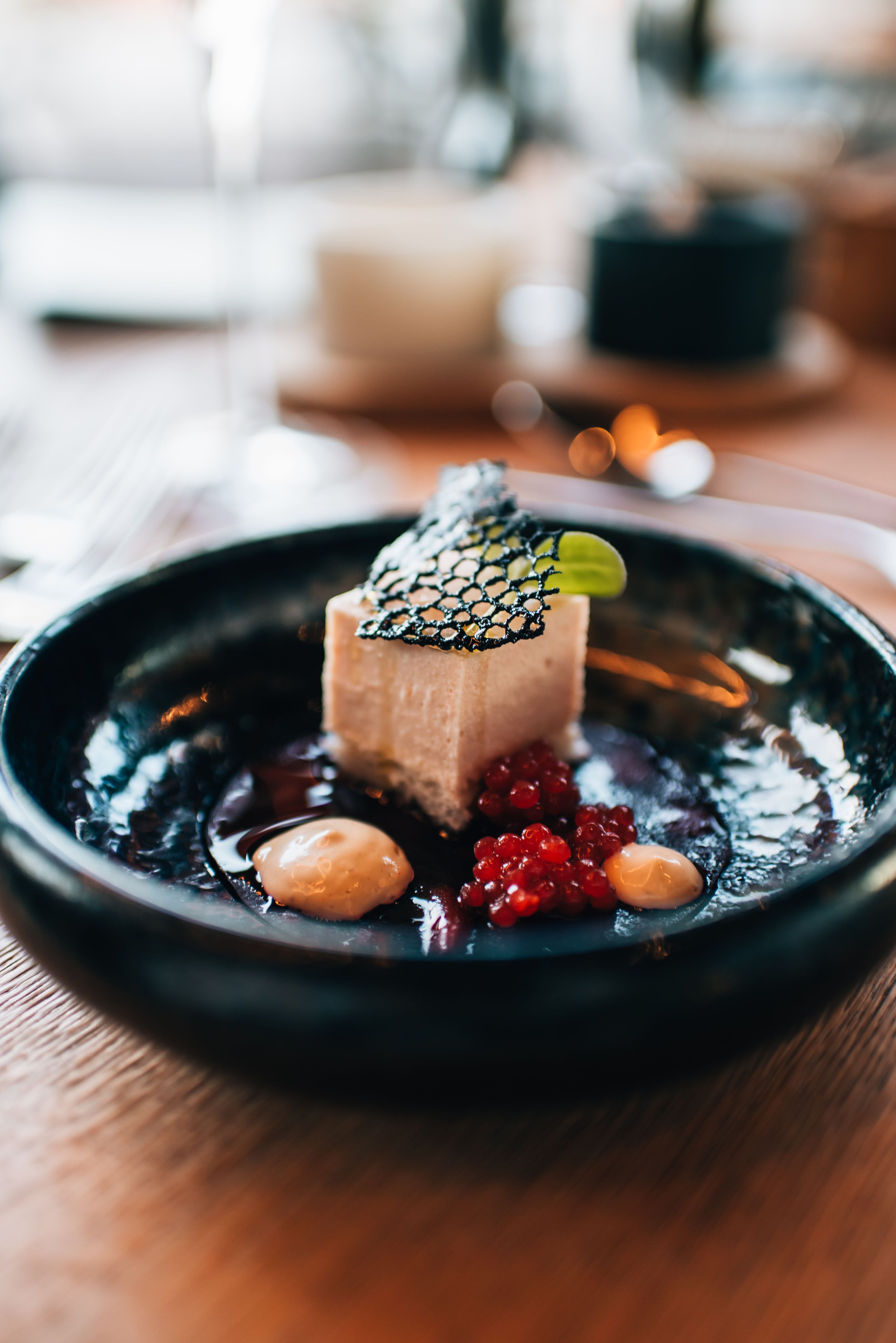 Moderne Weingut-Architektur bei Dämmerung mit beleuchteten Innenräumen und umliegenden Gebäuden.