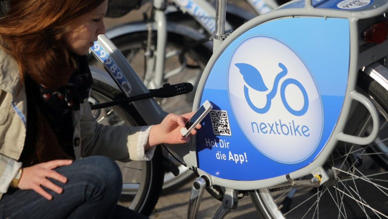 Frau scannt QR-Code an einem Nextbike-Leihrad mit ihrem Smartphone.
