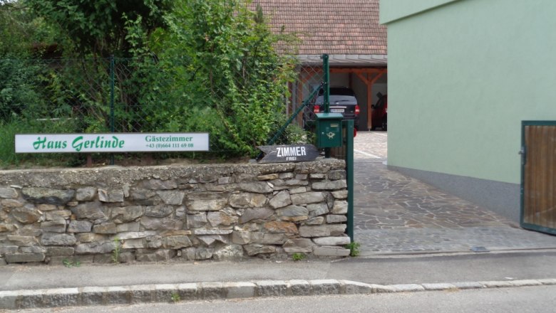 Eingang zu Haus Gerlinde mit Schild und Steinmauer.