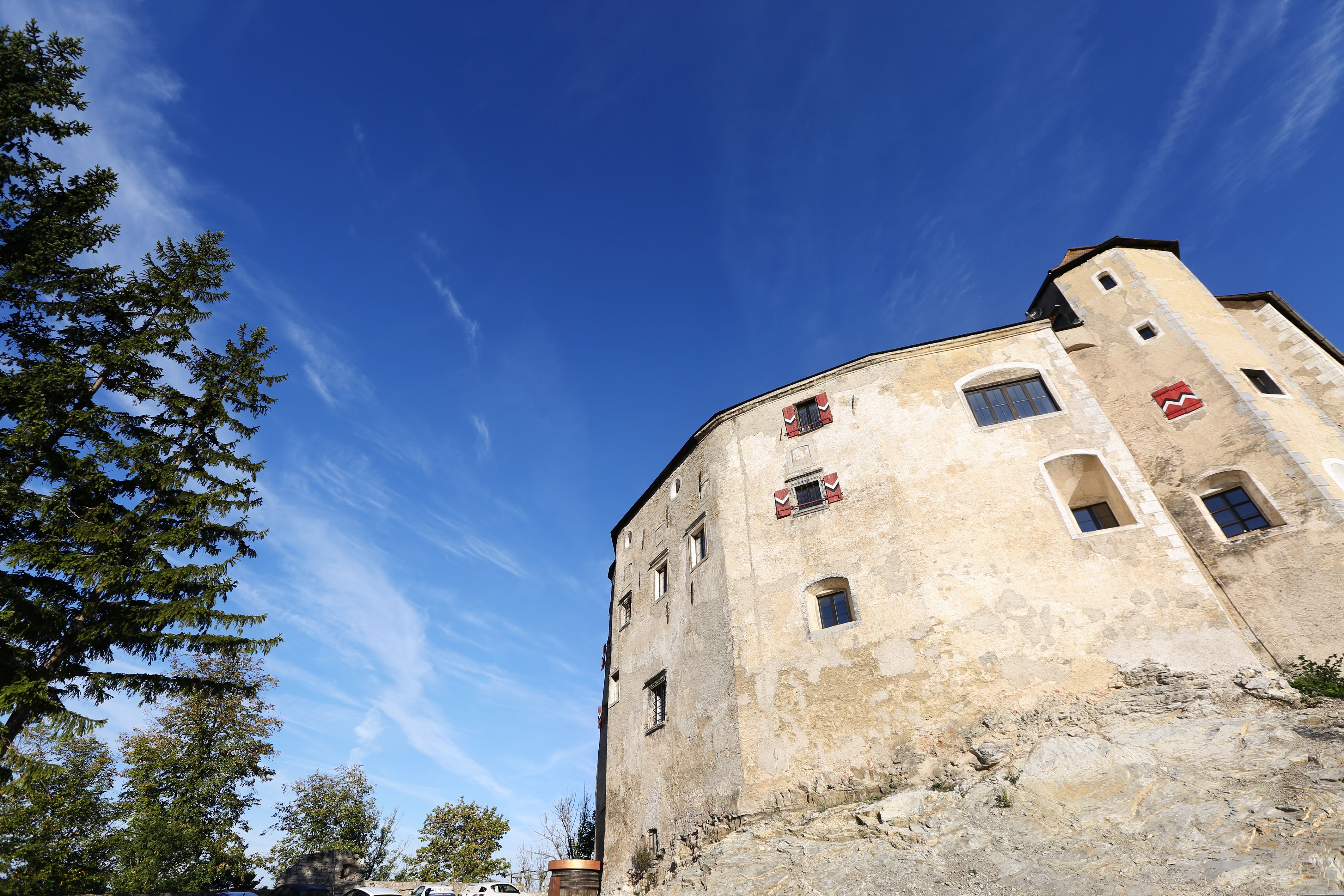 Burg Plankenstein vor blauem Himmel mit Bäumen im Vordergrund.