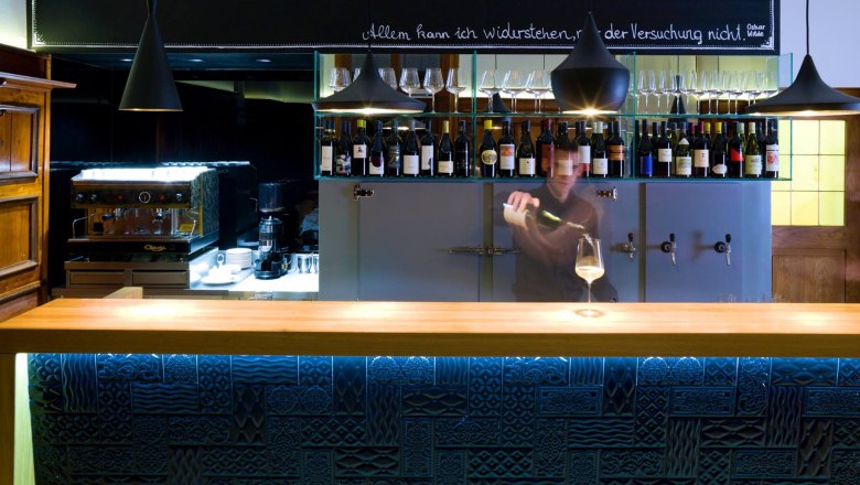 Bar mit vielen Weinflaschen im Hintergrund und Bartender