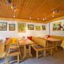 Innenansicht eines Heurigenlokals mit Holzmöbeln und Gemälden an der Wand.