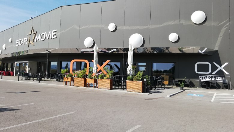 Au&szlig;enansicht von Star Movie Kino und OX Steaks & Grill mit Terrasse.