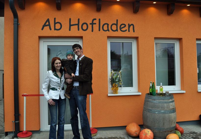 Familie vor dem Ab Hofladen Schäfer in Maria Ellend, mit Kürbissen und Weinfass dekoriert.
