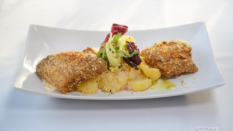Karpfenfilet in Mohn-Hanf-H&uuml;lle mit Kartoffelsalat und Salatgarnitur auf wei&szlig;em Teller.