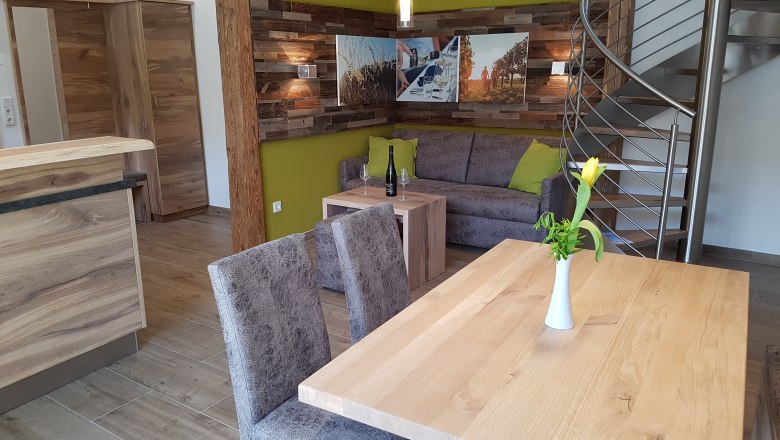 Modernes Appartement mit Holzm&ouml;beln, grauem Sofa, gelber Wand und Wendeltreppe.