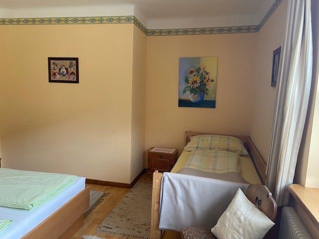 Ein Zimmer mit zwei Betten, einem Einzelbett und einem Doppelbett, dekoriert mit Blumenbildern an den Wänden.