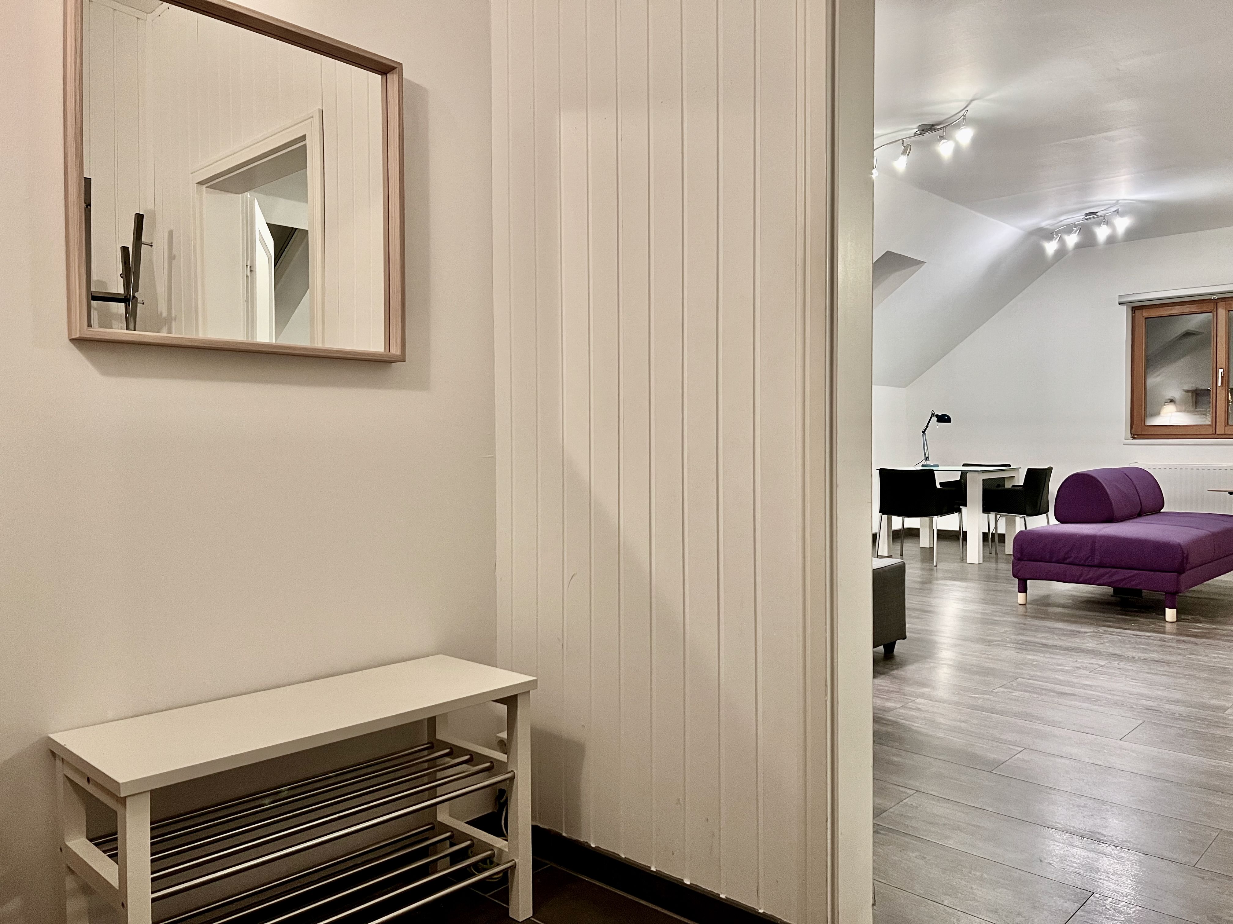 Innenansicht eines modernen Lofts mit lila Sofa und Esstisch.