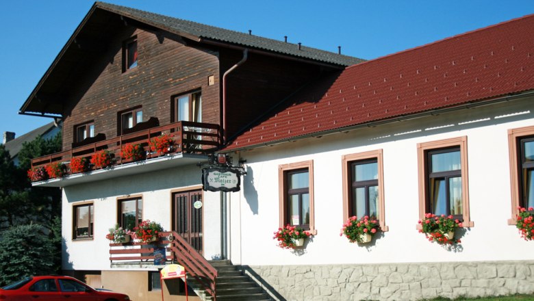Gasthaus Malzer mit Blumen geschmücktem Balkon und Fenstern.