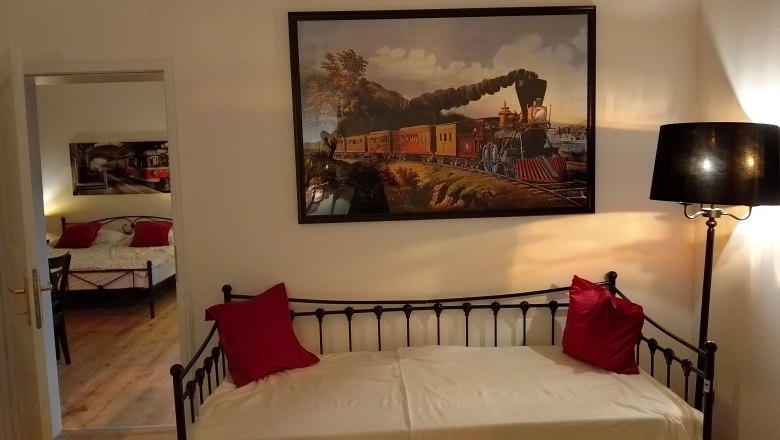 Zimmer mit Eisenbahndekor, Bett und Lampe.