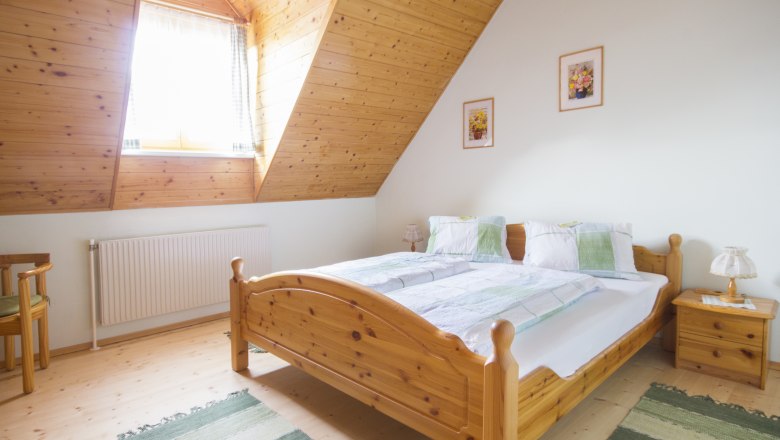 Gemütliches Schlafzimmer mit Holzmöbeln und Dachschräge.