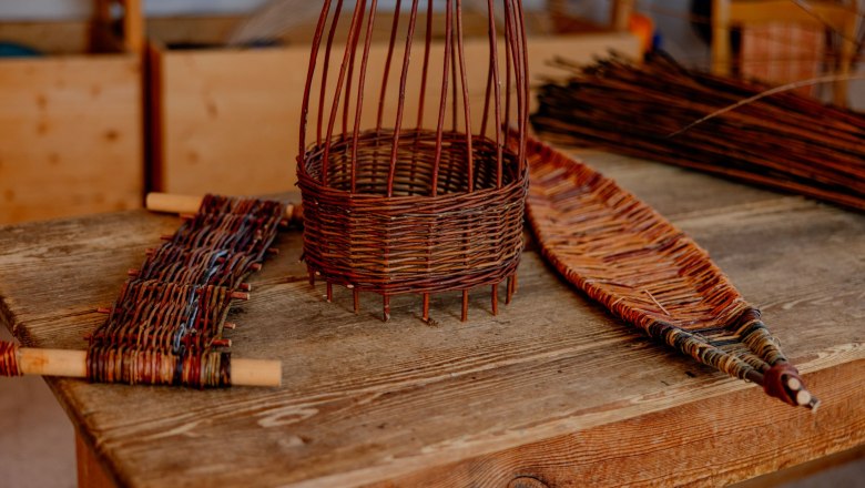 Geflochtene Korbwaren auf einem Holztisch in einer Werkstatt.