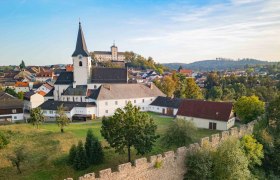 Luftaufnahme einer Stadt mit Kirche und Stadtmauer im Vordergrund.