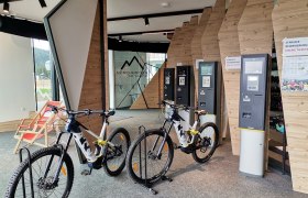 Innenansicht eines E-MTB Verleihs mit Fahrr&auml;dern und Ticketautomaten.