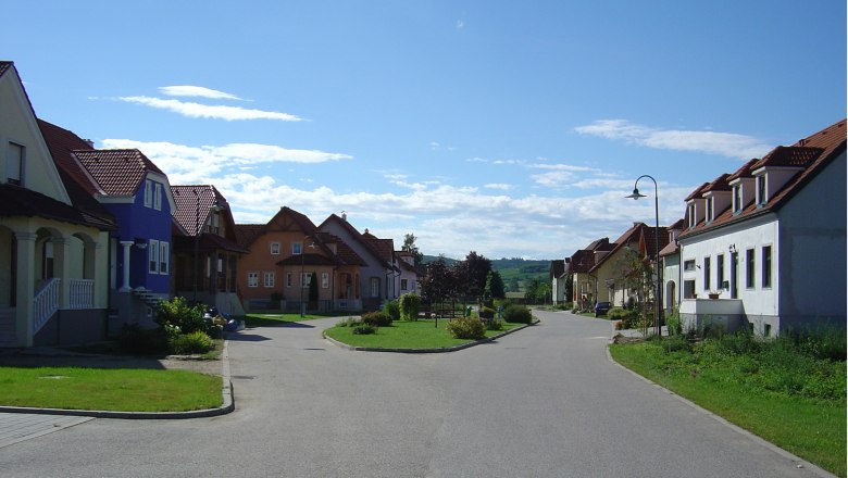 Straße in Alberndorf mit bunten Häusern und blauen Himmel.