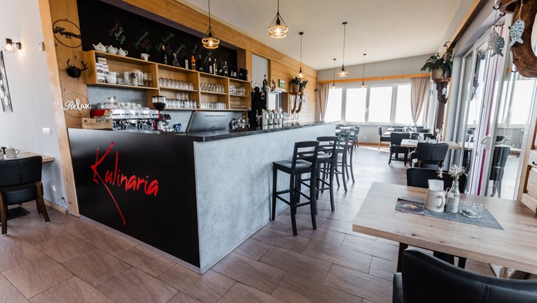 Innenansicht eines modernen Restaurants mit Bar und Sitzbereich.