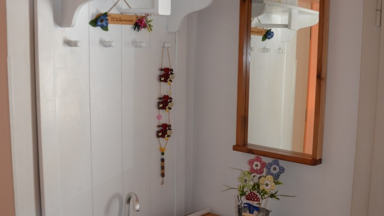 Eingangsbereich mit Garderobe, Spiegel, Schirmständer und Dekoration.