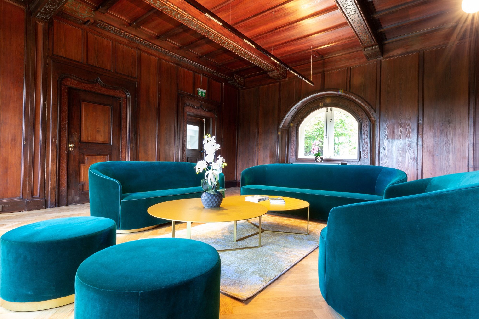 Elegantes Wohnzimmer mit grünen Sofas und Holzwänden.