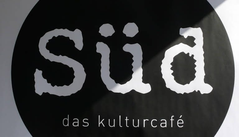 Logo des Kulturcaf&eacute;s S&uuml;d mit wei&szlig;er Schrift auf schwarzem Kreis.