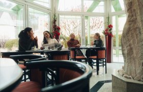 In der gem&uuml;tlichen Atmosph&auml;re der Konditorei N&ouml;bauer genie&szlig;en die G&auml;ste k&ouml;stliche Leckereien und anregende Gespr&auml;che. Die gro&szlig;en Fenster bieten einen herrlichen Blick auf die winterliche Landschaft der Wiener Alpen, w&auml;hrend die warmen Farben des Interieurs eine einladende Stimmung schaffen.