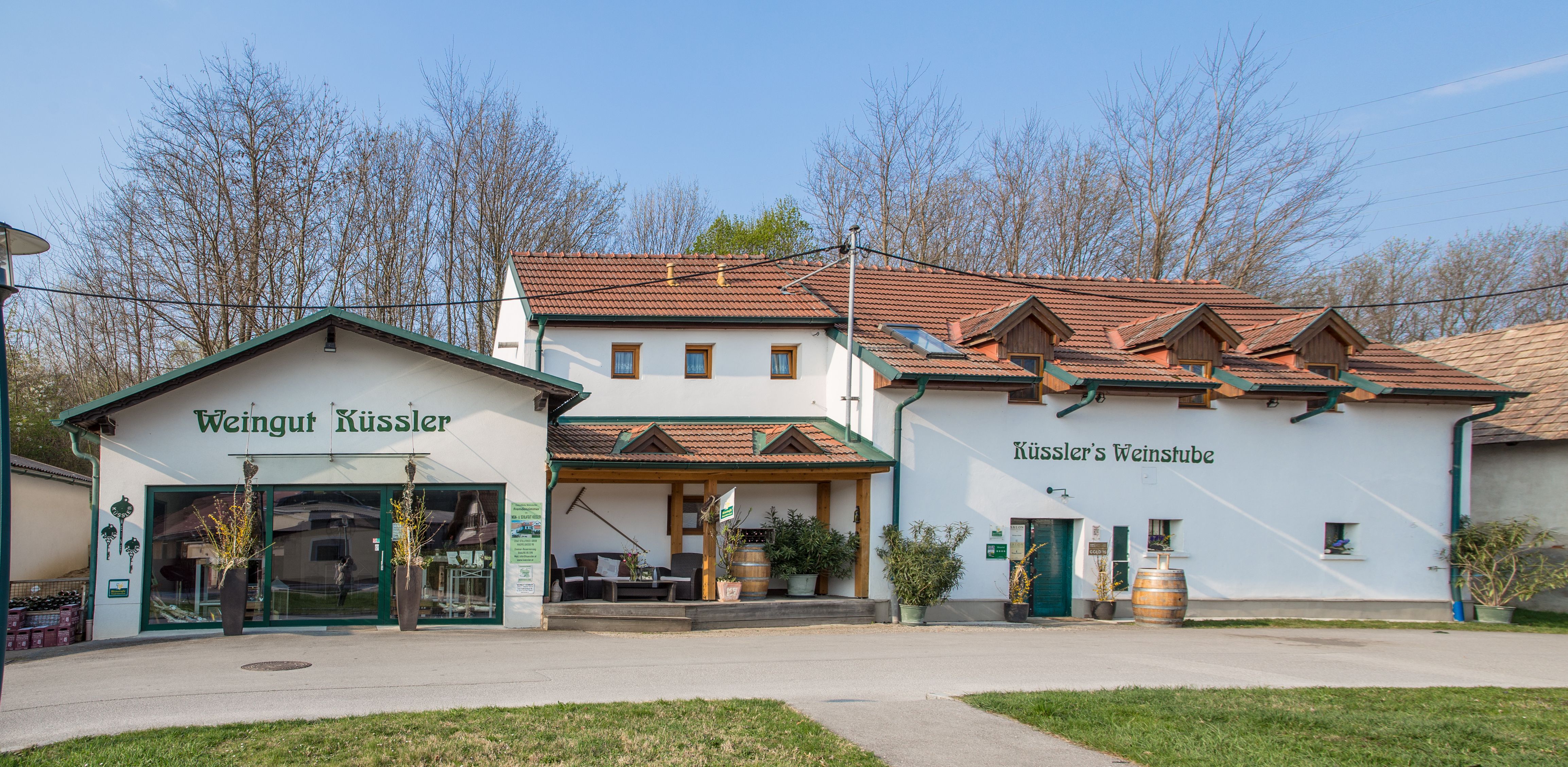 Weingut Küssler mit Weinbar und Terrasse, umgeben von Bäumen.