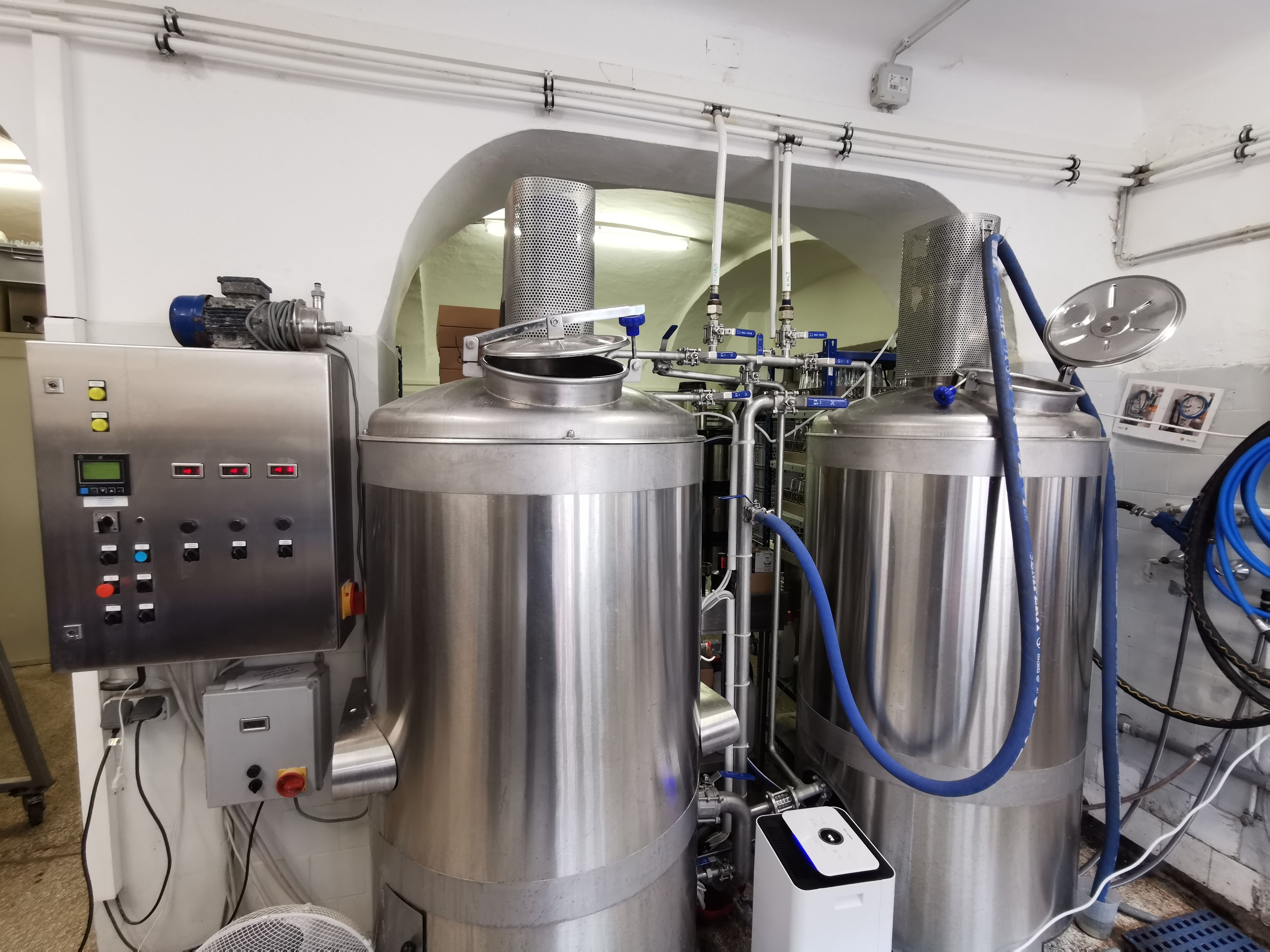 Zwei große Edelstahl-Braukessel in einer Brauerei mit Steuerungspanel.