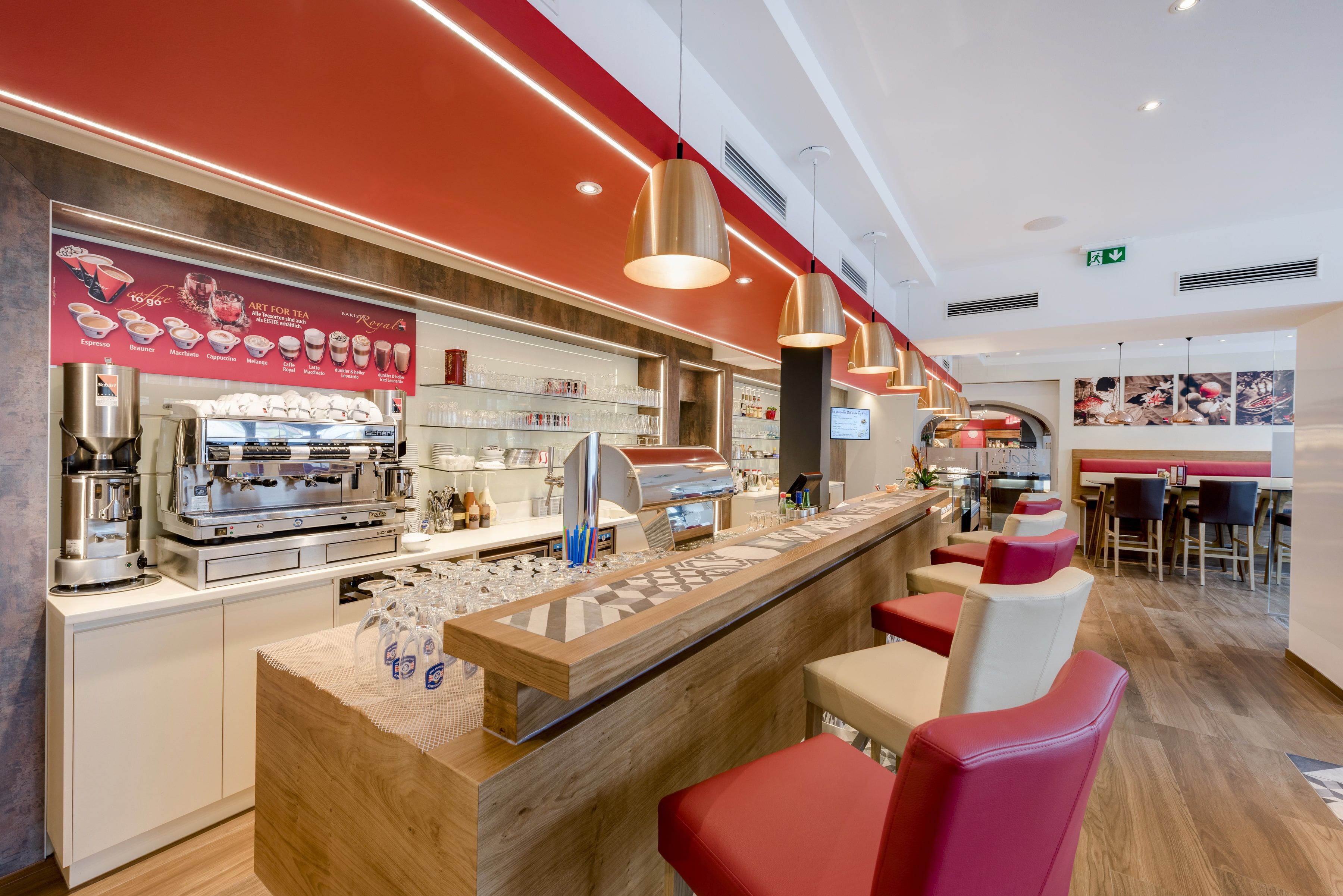 Innenansicht eines modernen Bistros mit Theke, Kaffeemaschine und Barhockern.